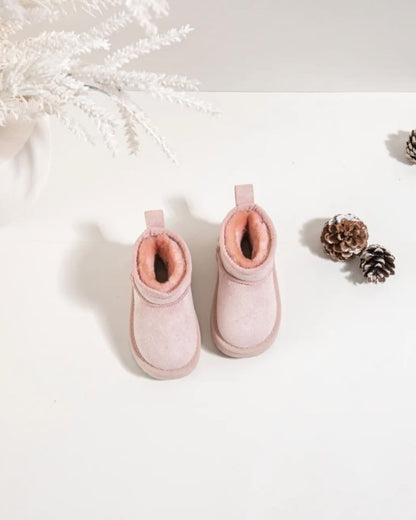 Pair of pink boots on a white surface with decorative elements.