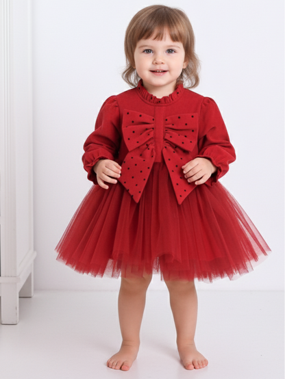 Child wearing a red dress with a large bow on a white background