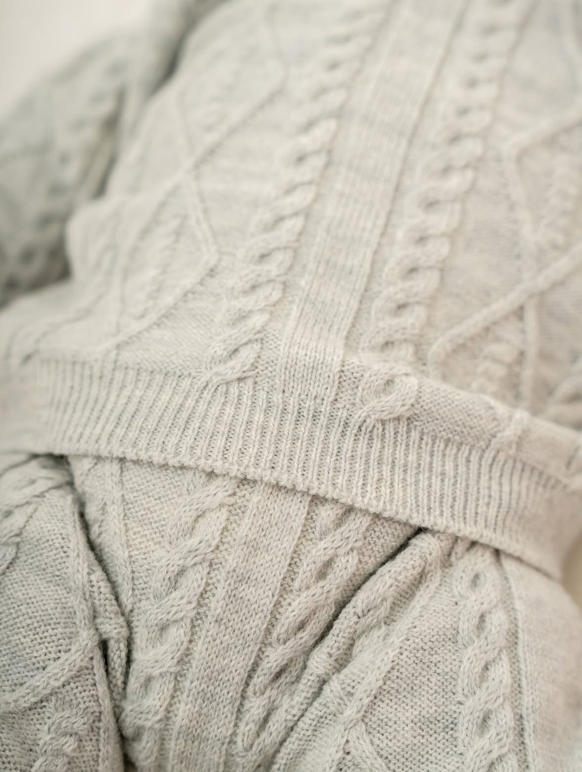 Close-up of a textured beige sweater with cable knit pattern.