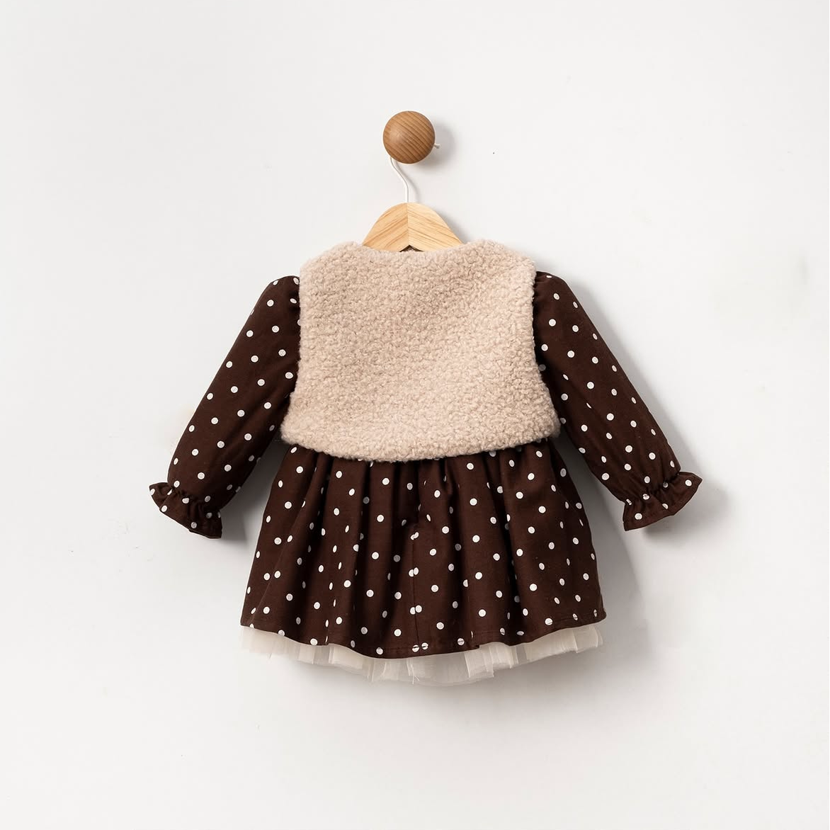 Children's outfit with brown polka dot dress and beige sweater on a white background
