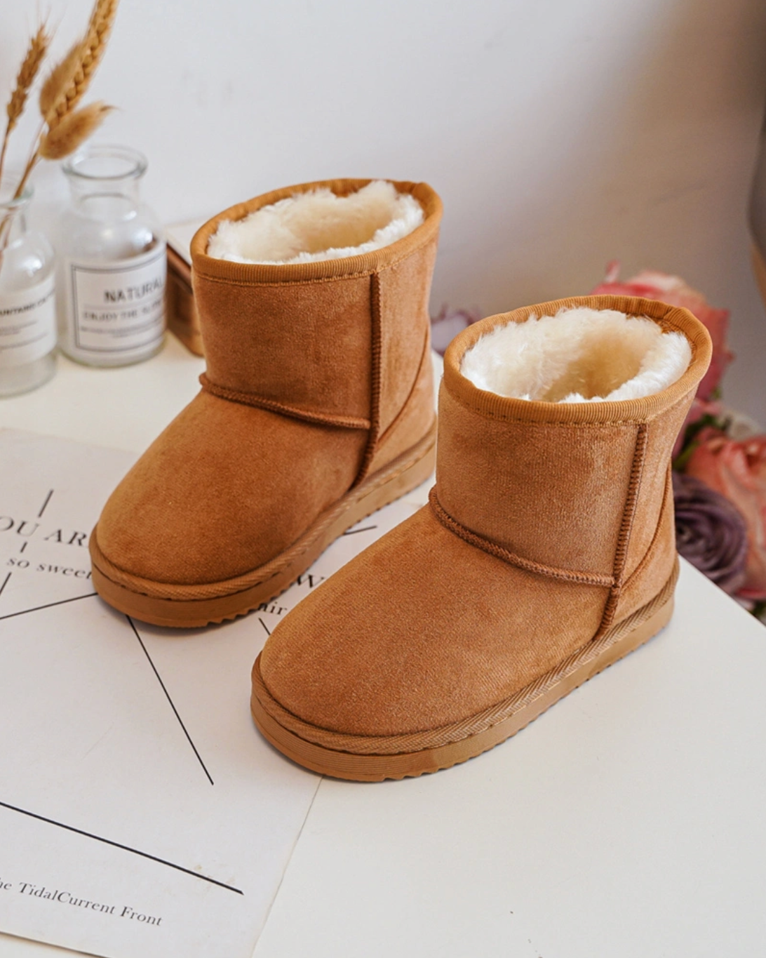 Pair of brown UGG boots on a white surface with a blurred background