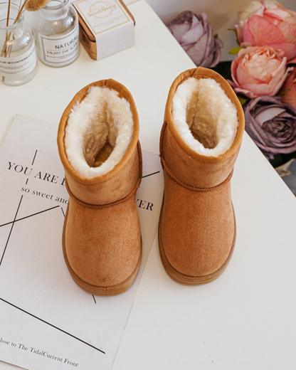 Pair of brown boots with fur lining on a white surface with floral decorations.