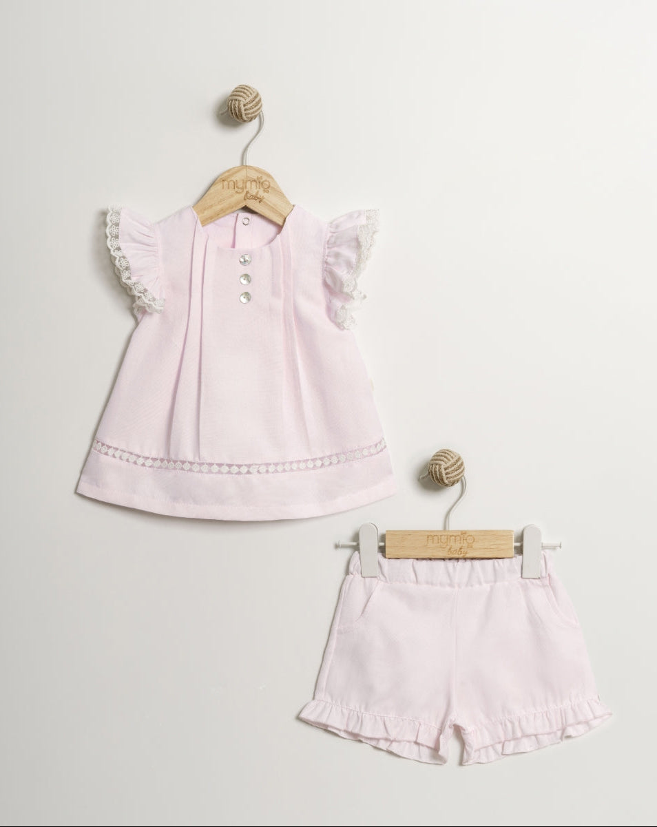 Pink children's outfit with top and shorts on hangers against a light gray background
