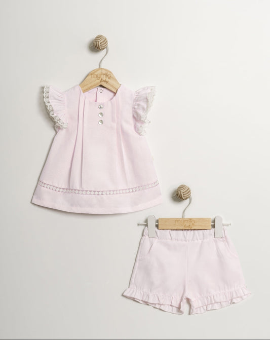 Pink children's outfit with top and shorts on hangers against a light gray background