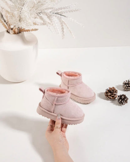 Pink baby boots on a white surface with decorative elements.